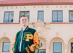 PHS student in letter jacket poses in front of Old Main